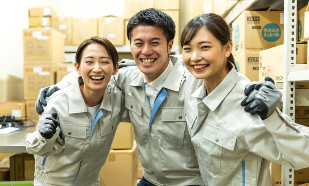 倉庫で笑顔の作業スタッフ3人。自社出荷の現場イメージ