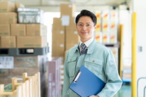 倉庫でクリップボードを持つ作業員。WMS(倉庫管理システム)による入荷・在庫・出荷管理のイメージ
